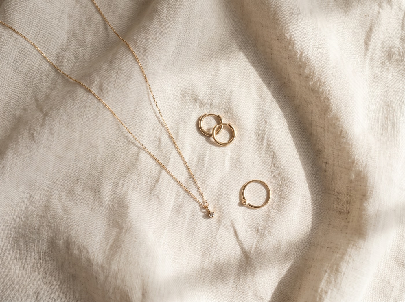 Minimal gold jewelry arranged on linen